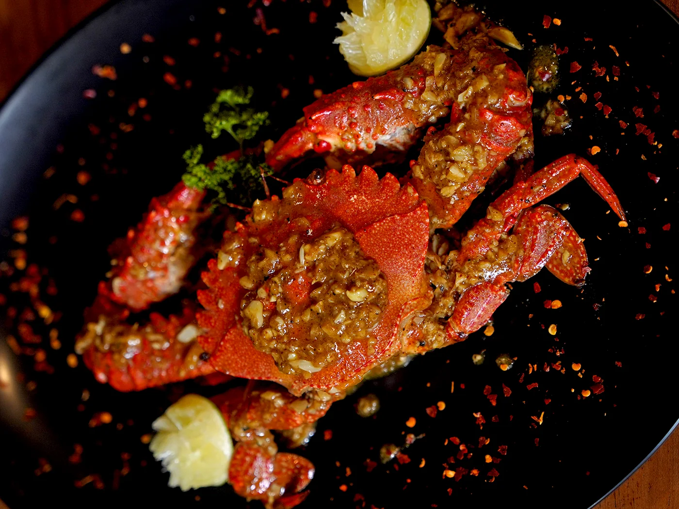 Cangrejo entero a la parrilla con salsa de ajo, servido con lima
