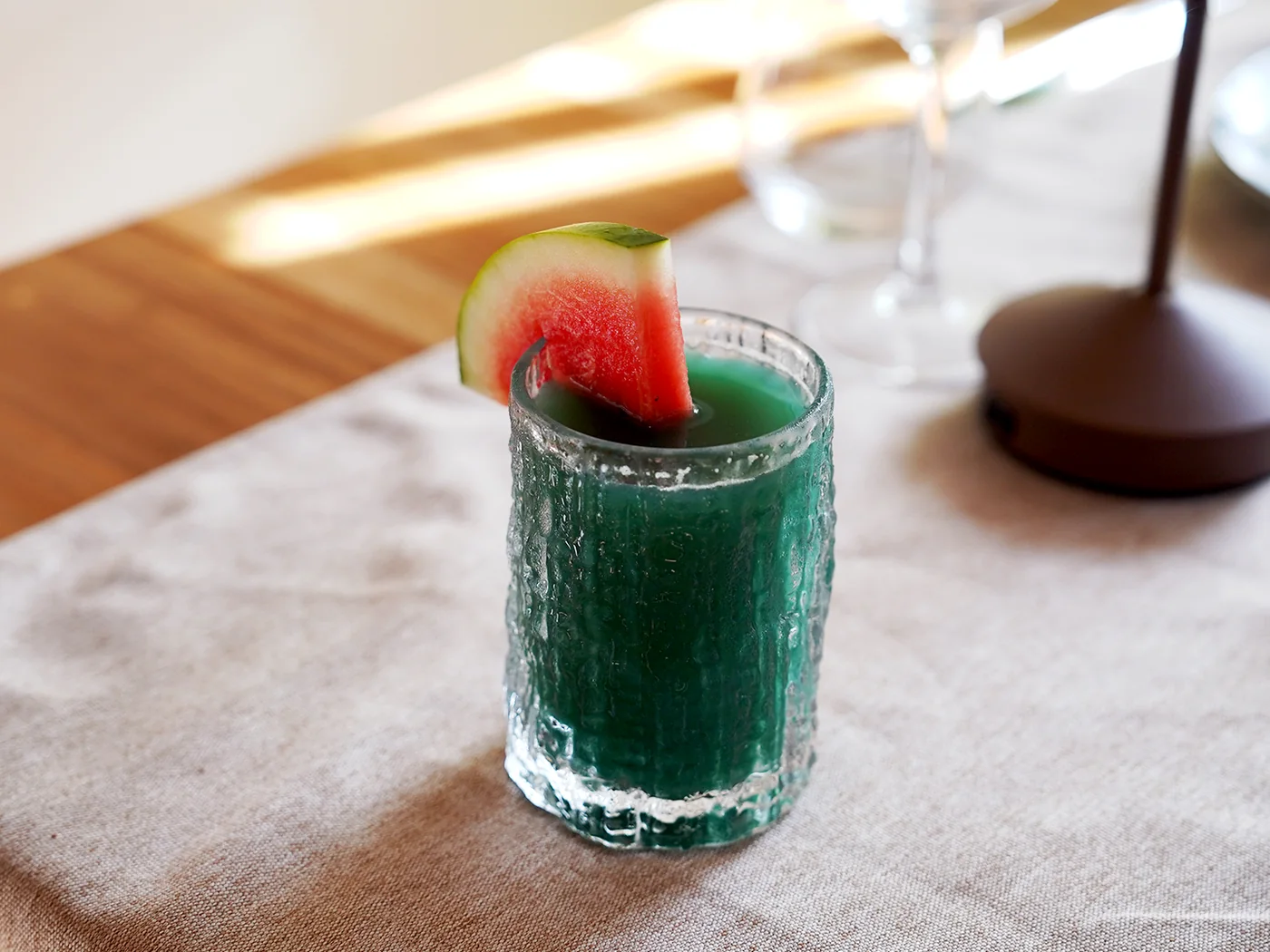 Cóctel verde guarnecido con una rodaja de sandía, sobre la mesa